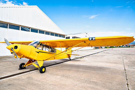 Yellow single-engine ultralight aircraft on the airfield runway.	
