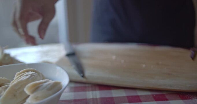 Detailed close-up of a person's hands preparing a fresh banana, peeling and then carefully slicing it on a wooden cutting board. Perfect for demonstrating healthy eating and food preparation.