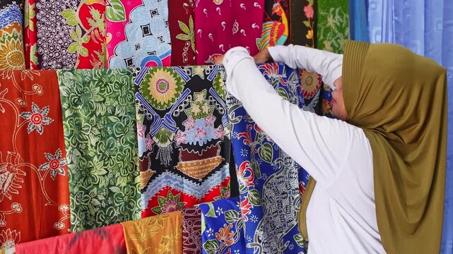 Muslim woman choosing traditional handmade batik fabric