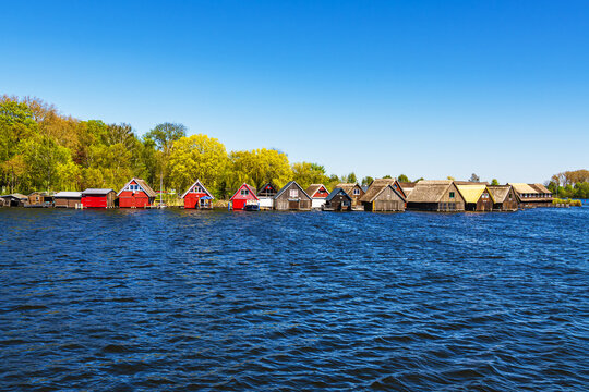 B&auml;ume und Bootsh&auml;user an der M&uuml;ritz im Fr&uuml;hling in R&ouml;bel