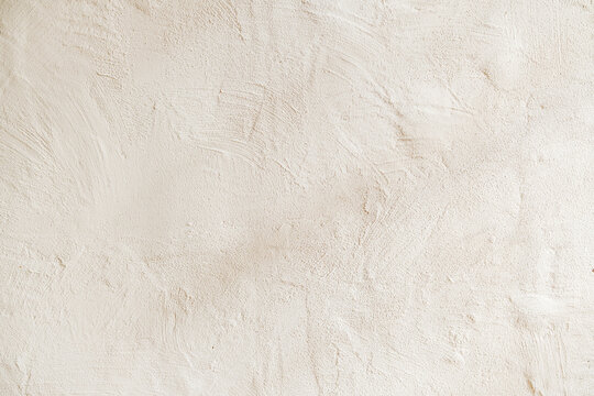 Textured pale wall surface with fine grit and subtle brush strokes, neutral background detail.