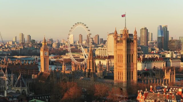 Golden hour light illuminating Palace of Westminster, iconic Big Ben, London Eye with the River Thames and central London's cityscape in the background