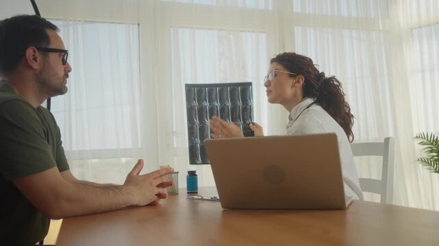 Female radiologist explaining lumbar spine MRI results to patient in clinic