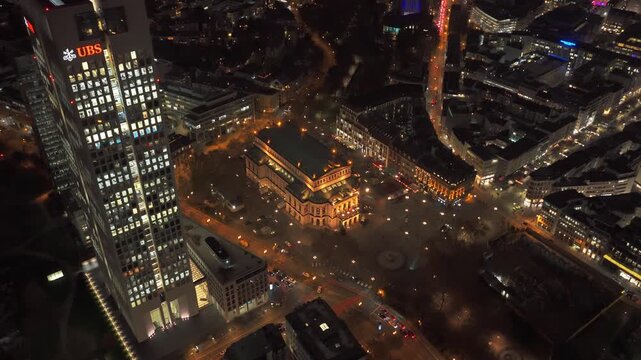 Nighttime aerial view of Frankfurt's financial district, featuring Alte Oper concert hall and illuminated modern skyscrapers