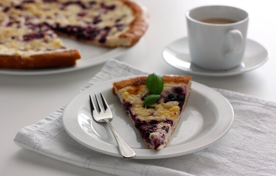 Traditional Czech valassky frgal blueberry pastry on white plate with coffee, rustic homemade dessert from Wallachia region, sweet bakery food photography with copy space, minimal light background