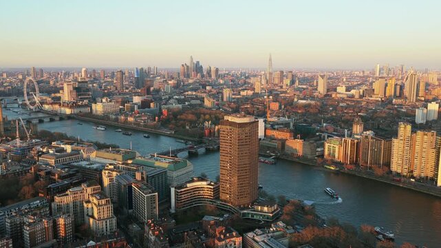 London skyline showing the River Thames with boats and Millbank Tower in Westminster with financial district in the background at sunset