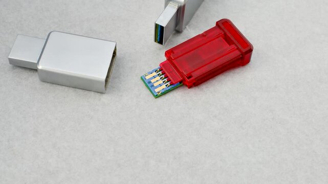 Close-up of a disassembled USB flash drive on a white background, revealing its internal complexity. Close-up of an open USB flash drive, exposing circuits and connections, on a white surface.