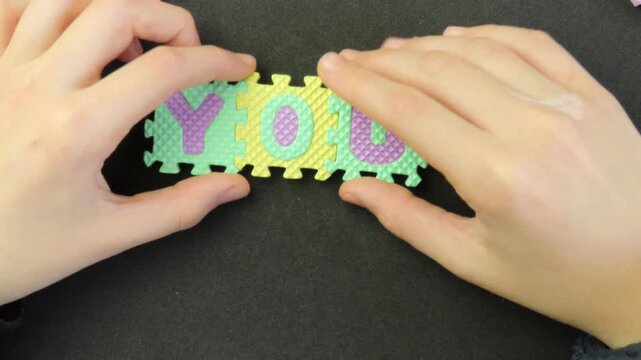 Closeup of child's hands playing with a eva foam letters puzzle. Child's hands playing with an educational toy. Kid's hands building blocks.