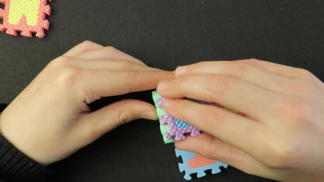 Closeup of child's hands playing with a eva foam letters puzzle. Child's hands playing with an educational toy. Kid's hands building blocks.