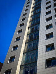 Fototapeta premium Modern residential building with dramatic perspective and blue sky, urban architecture background