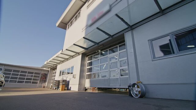 Beginning of the working day in the professional car repair shop, sunlight enters the spacious workshop as the roller doors open.