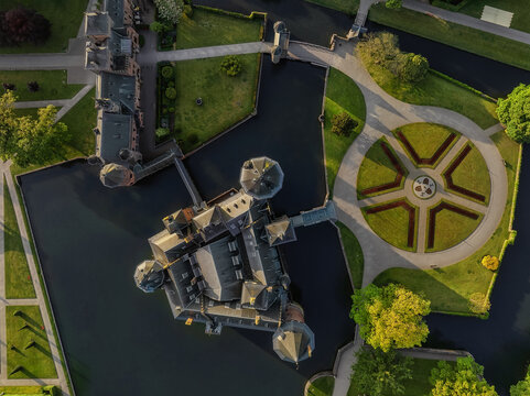 Aerial view of De Haar Castle featuring its Gothic towers, dark moat water, and symmetrical circular garden patterns in Utrecht, Utrecht, Netherlands.