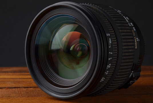 PERPIGNAN, FRANCE - MAY 5, 2026: A Sigma 17-70mm 2.8-4.5 DC Macro lens for digital SLR cameras, placed on a wooden surface. This versatile zoom lens was a popular high-performance alternative to stand