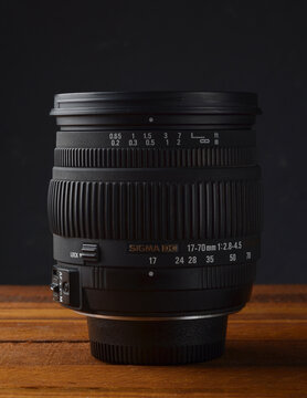 PERPIGNAN, FRANCE - MAY 5, 2026: A Sigma 17-70mm 2.8-4.5 DC Macro lens for digital SLR cameras, placed on a wooden surface. This versatile zoom lens was a popular high-performance alternative to stand