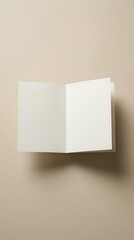 Naklejka premium Blank folded greeting card mockup floating against a warm beige background, showing clean white paper with soft shadow for branding.