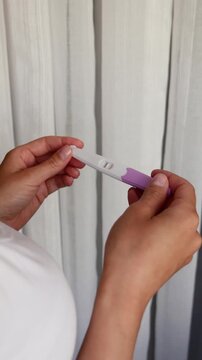Woman hands checking negative pregnancy result, vertical close-up video, single line on test stick, trying to conceive, hopeful waiting, home healthcare.
