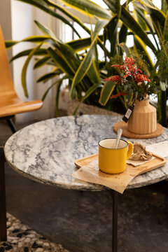 empty coffee mug with spoon and crumpled napkin at a hip cafe with marble table next to window with wood chairs