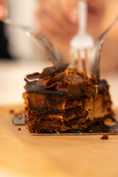 close up depth of field of fork cutting into rich decadent layered chocolate cake in a restaurant