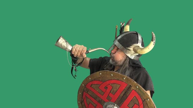 Bearded man in horned Viking helmet raises a silver war horn to his lips in a powerful battle cry. Round Celtic shield, quiver of arrows. Full action cycle on green screen for chroma key compositing