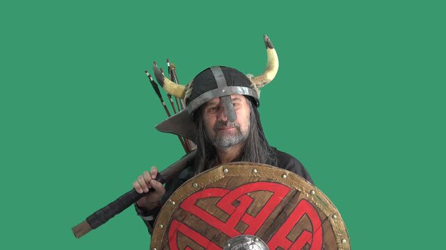 Bearded man in Viking costume on green screen &mdash; horned helmet, iron face guard, round Celtic shield, battle axe, arrows. Expressions range from fierce to smiling thumbs-up. Clean chroma key, compositi