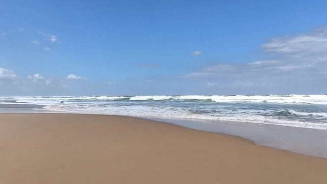 Powerful cinematic footage of massive ocean waves rolling toward the shoreline from a stormy sea under bright sunlight. 
