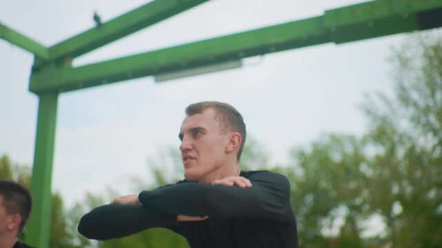 focused white man leading arm stretches, instructor role shifts between coach and mentor, dynamic motion under green canopy, cadence driven warmup, determined breathing and crisp posture across frames