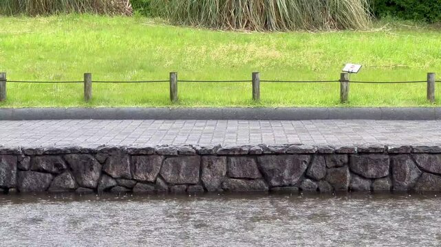 Rain taps water near stone wall
