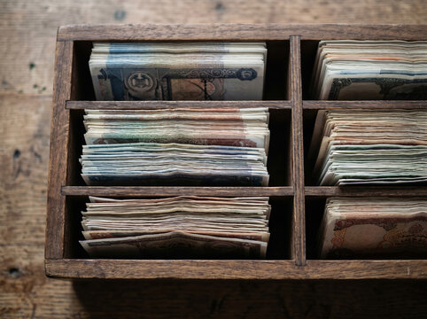 Different currencies sorted in a wooden drawer or tray