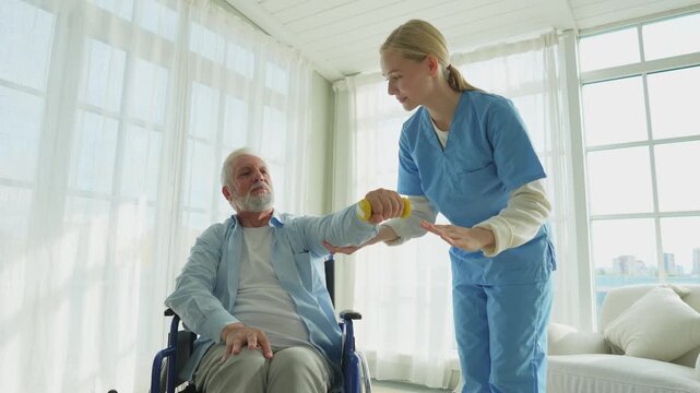 Support rehabilitation healthcare. Nurse helps old man patient in wheelchair picking up dumbbells. Paralyzed man in chair for people with disability doing sports exercise with nurse. Medical caregiver