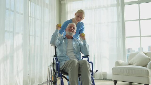 Support rehabilitation healthcare. Nurse helps old man patient in wheelchair picking up dumbbells. Paralyzed man in chair for people with disability doing sports exercise with nurse. Medical caregiver