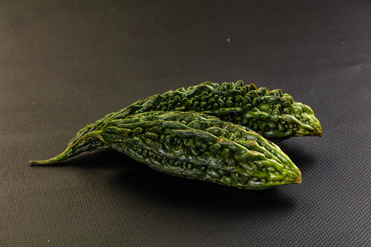 Whole bitter gourds on a dark textured slate background with copy space