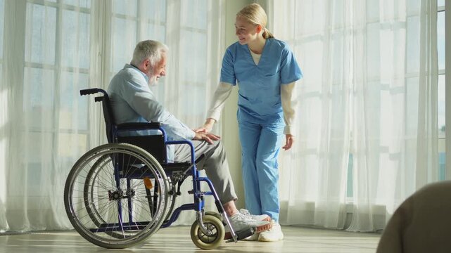 Help support retirement healthcare. Nurse helping old man in wheelchair. Patient and woman in nursing home for medical caregiver. Nurse taking care of paralyzed man in chair for people with disability