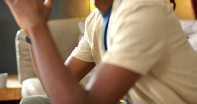 African man leaning forward hands at mouth covering face rubbing revealing profile on sofa thinking