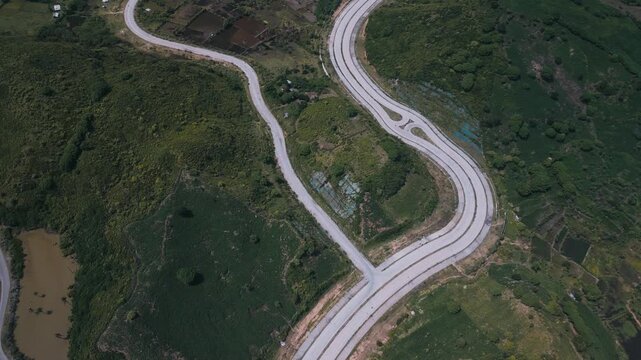 Path Winding Over Lush Landscape. Aerial View Of Curving Path Amidst Rich Foliage And Wetlands. Picture Taken From Above Showing Looped Highway Surrounded By Dense Woodland And Marshes,Lombok