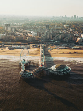 Aerial view of De Pier with its iconic Ferris wheel and observation tower stretching into the North Sea at sunset in Den Haag, Zuid-Holland, Netherlands.