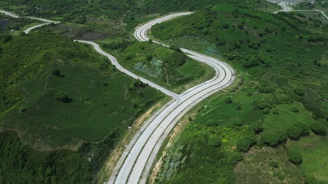Path Winding Over Lush Landscape. Aerial View Of Curving Path Amidst Rich Foliage And Wetlands. Picture Taken From Above Showing Looped Highway Surrounded By Dense Woodland And Marshes,Lombok