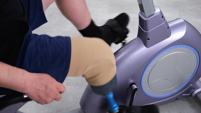 Amputee with prosthetic leg training on stationary exercise bike
