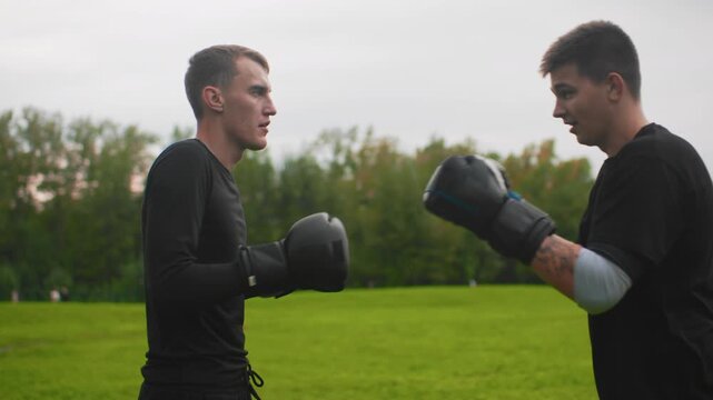white men sparring outdoors on grass, disciplined mitt work and focused exchanges between amateur boxers slow controlled jabs, defensive blocks, stance adjustments and coachlike guidance