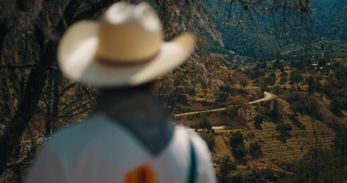 Cinematic over-the-shoulder shot of a catholic missionary overlooking a rural landscape in Mexico