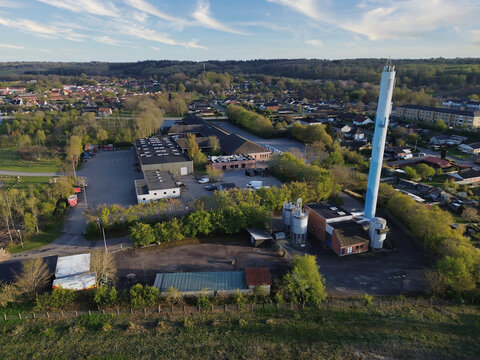 District heating plant in Aabenraa, Denmark, with its tall blue chimney rising above industrial buildings and residential areas