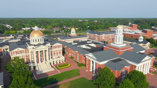 Christopher Newport University campus, a sweeping aerial drone view showcasing the grand neoclassical brick architecture, iconic golden domes, and manicured green lawns of the CNU campus in Newport Ne