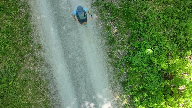 Trail runner seen from bird eye view on a natural path, surrounded by landscape, expressing connection to nature, mental clarity, balance and happiness through movement.