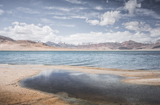 Mountain landscape, a cold high-altitude lake against the backdrop of rocky peaks and ridges with snow and glaciers, a panorama in the Tien Shan Mountains in the Pamirs, a lake with waves