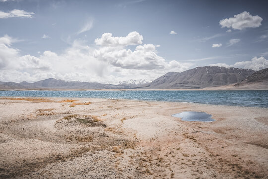 Mountain landscape, a cold high-altitude lake against the backdrop of rocky peaks and ridges with snow and glaciers, a panorama in the Tien Shan Mountains in the Pamirs, a lake with waves