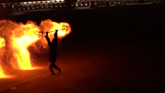 Fire performer spinning flames and sparks at night