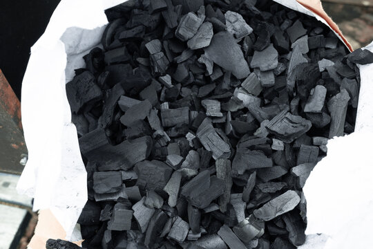 Natural wood charcoal chunks in a white paper bag for BBQ.