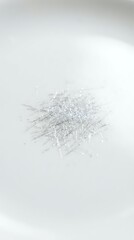 Fototapeta premium Pile of fine silver metallic threads scattered on white background creating abstract texture pattern for craft and textile design projects.