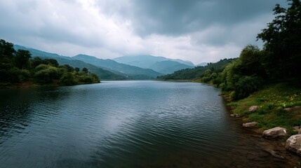 Obraz premium Wide river flowing through lush mountainous valleys under a heavy overcast sky