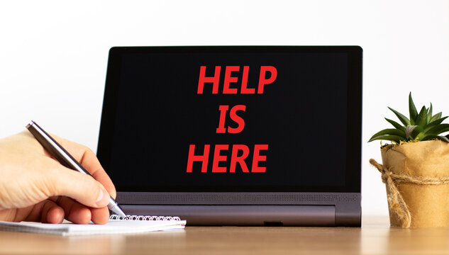 Help is here and support words symbol. Concept words Help is here on beautiful black tablet. Beautiful white background. Businessman hand. Business help is here and support concept. Copy space.
