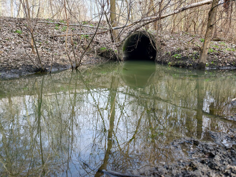 Large reinforced concrete pipe installed under dirt road to prevent washout. Large-diameter reinforced concrete pipe under forest dirt road for water drainage